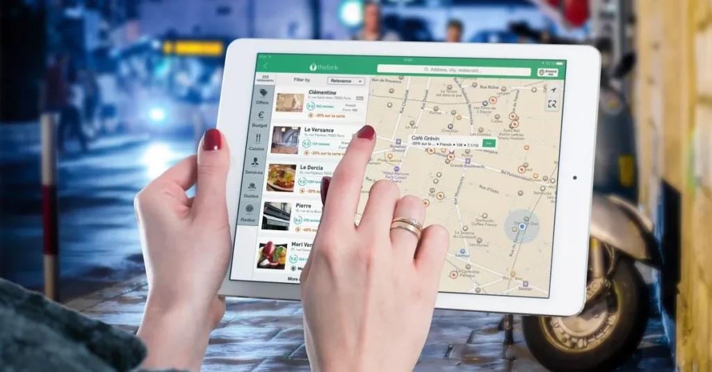 Hands using a digital map on a tablet in an urban setting at night, illustrating navigation and technology.