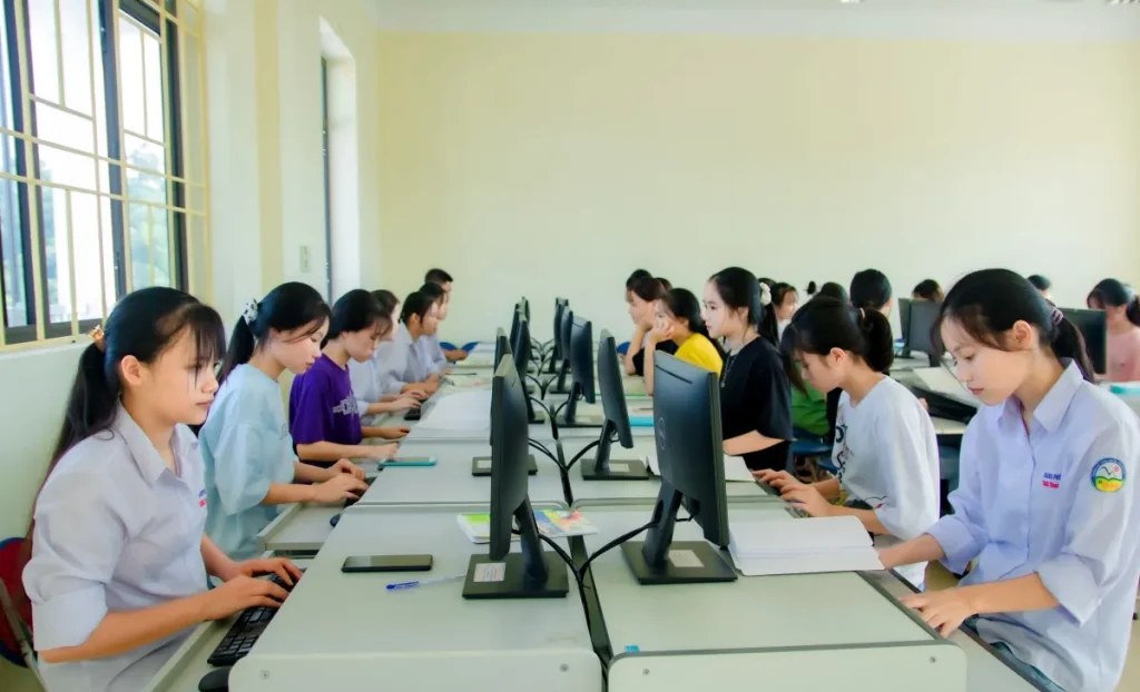 A group of students focusing on computers during a class in a university setting, working indoors.
